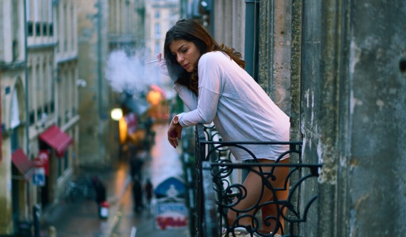 Women is smoking at the balcony of her apartment