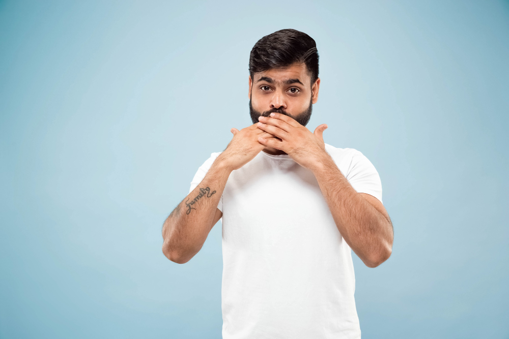 half-length-close-up-portrait-young-hindoo-man-white-shirt-blue-background-human-emotions-facial-expression-sales-ad-concept-negative-space-covering-his-face-with-his-hands