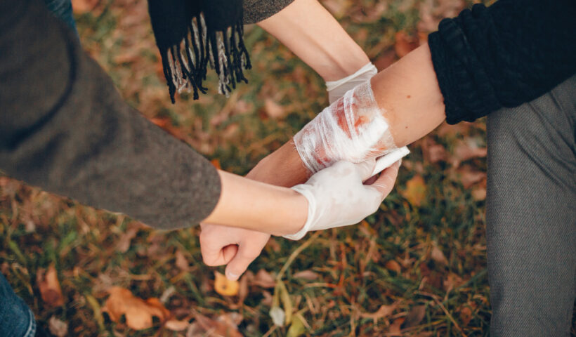 providing-first-aid-park-man-bandaged-injured-arm-guy-helps-friend