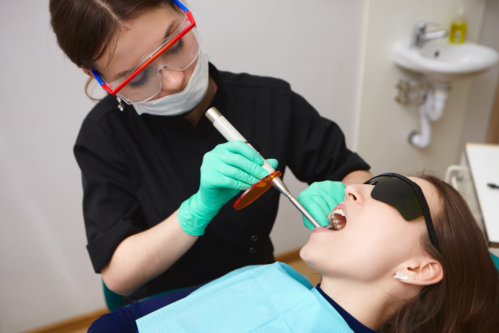 young-patient-black-goggles-getting-her-teeth-treated-by-female-hygienist-using-dental-curing-light
